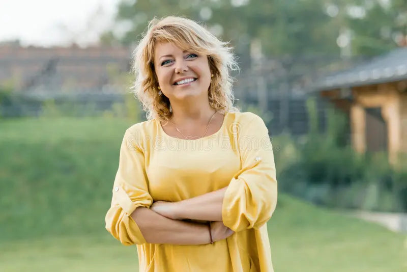 files/outdoor-portrait-positive-confident-mature-woman-smiling-female-blonde-yellow-dress-arms-crossed-near-house-133914157.webp
